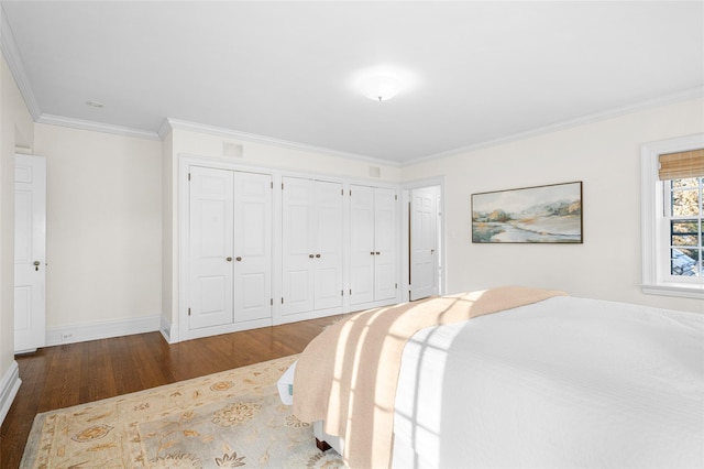 bedroom with ornamental molding, dark hardwood / wood-style floors, and two closets