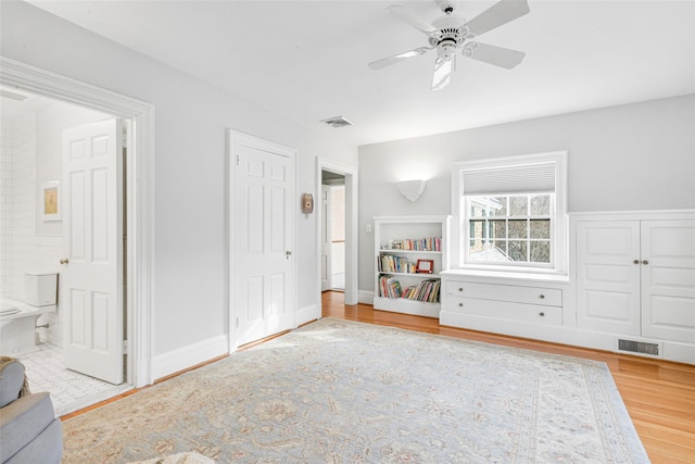 unfurnished bedroom featuring ceiling fan, ensuite bathroom, and hardwood / wood-style floors