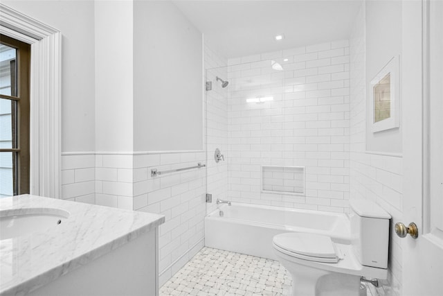 full bathroom featuring tiled shower / bath, tile walls, tile patterned flooring, vanity, and toilet