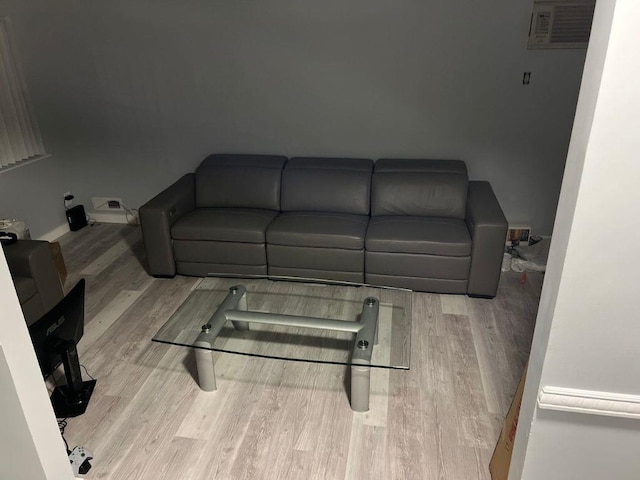 living room with a wall mounted AC and light hardwood / wood-style flooring