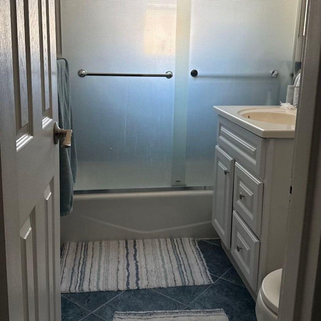 full bathroom with shower / bath combination with glass door, tile patterned floors, vanity, and toilet