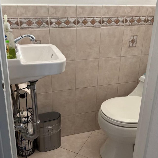 bathroom featuring sink, toilet, tile patterned flooring, and tile walls