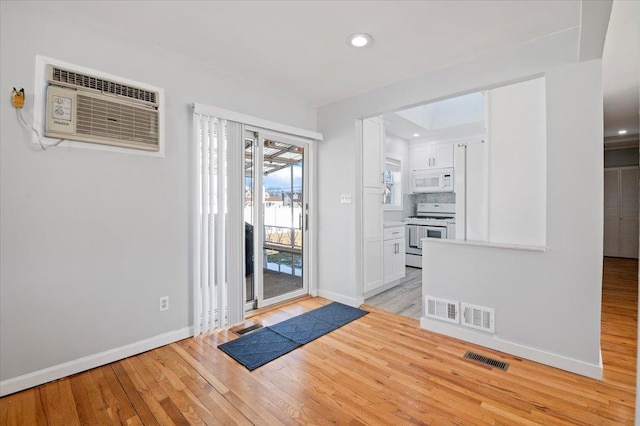 interior space featuring a wall mounted air conditioner and light wood-type flooring