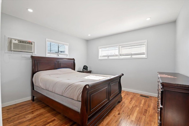 bedroom featuring light hardwood / wood-style floors and an AC wall unit