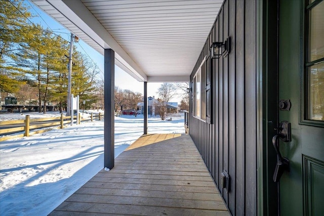 snow covered deck featuring covered porch