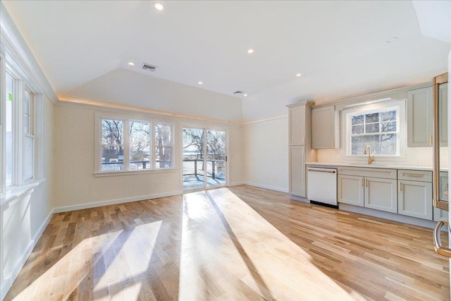 kitchen with sink, dishwasher, light hardwood / wood-style floors, decorative backsplash, and vaulted ceiling