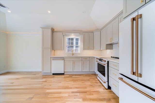 kitchen with vaulted ceiling, sink, backsplash, light hardwood / wood-style floors, and white appliances