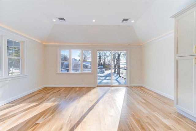 spare room with vaulted ceiling, plenty of natural light, and light hardwood / wood-style floors