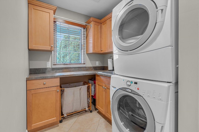 washroom featuring cabinets, stacked washer / drying machine, and light tile patterned floors