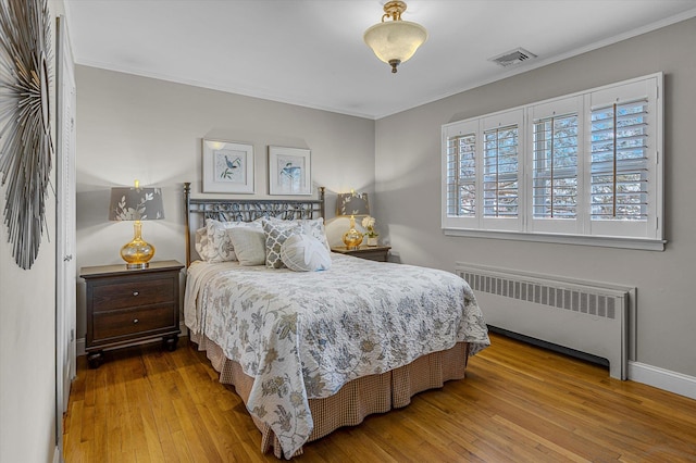 bedroom featuring crown molding, radiator, and hardwood / wood-style floors