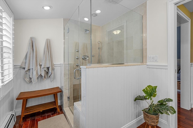 bathroom featuring plenty of natural light, a shower with door, and a baseboard heating unit