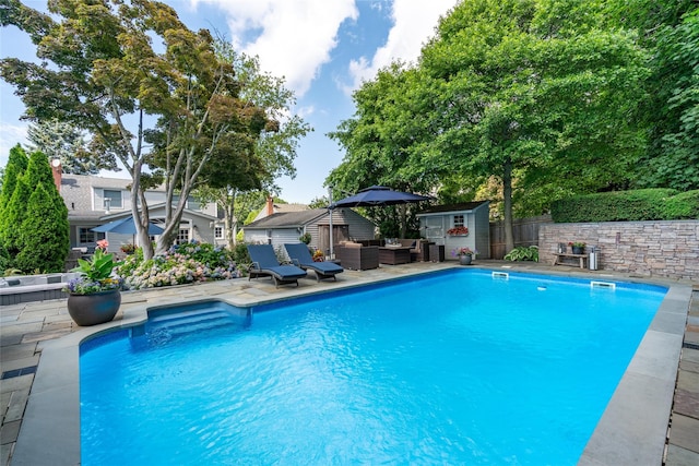 view of swimming pool with a patio, outdoor lounge area, and a storage unit