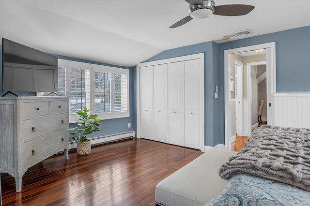 bedroom featuring vaulted ceiling, a baseboard heating unit, ceiling fan, dark wood-type flooring, and a closet