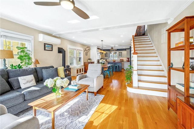 living room featuring crown molding, light hardwood / wood-style flooring, ceiling fan, an AC wall unit, and a wood stove