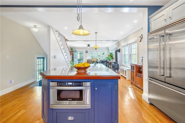 kitchen featuring a kitchen island, appliances with stainless steel finishes, pendant lighting, blue cabinets, and light hardwood / wood-style floors