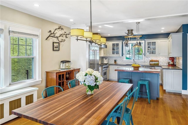 kitchen with hanging light fixtures, radiator, white cabinets, and light hardwood / wood-style flooring