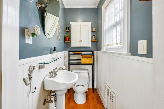 bathroom featuring radiator, crown molding, hardwood / wood-style floors, and toilet