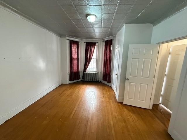 unfurnished room featuring wood-type flooring and radiator