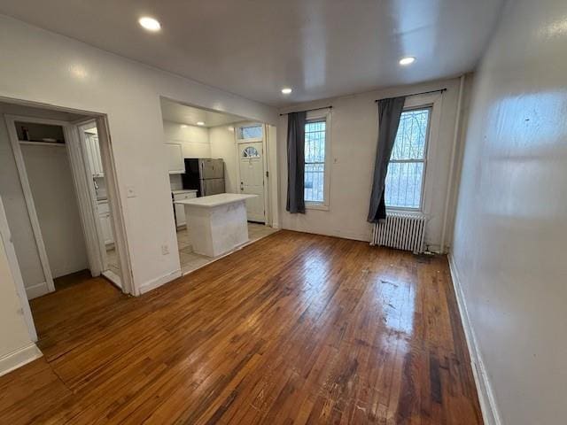 unfurnished living room featuring hardwood / wood-style flooring and radiator heating unit