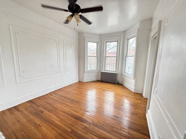 empty room with radiator, ceiling fan, and light hardwood / wood-style flooring