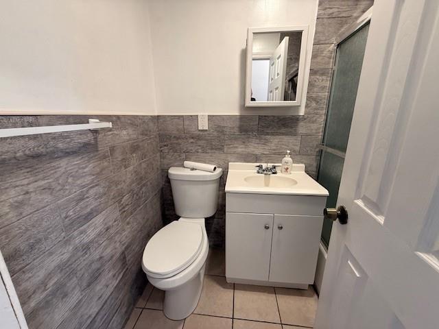 bathroom with vanity, tile walls, tile patterned floors, and toilet