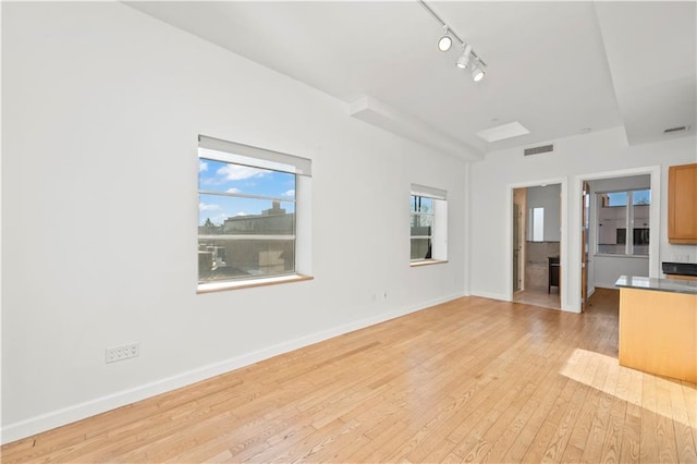 unfurnished living room featuring plenty of natural light, light wood finished floors, baseboards, and visible vents