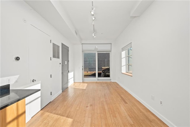 interior space featuring light wood-style flooring, track lighting, visible vents, and baseboards