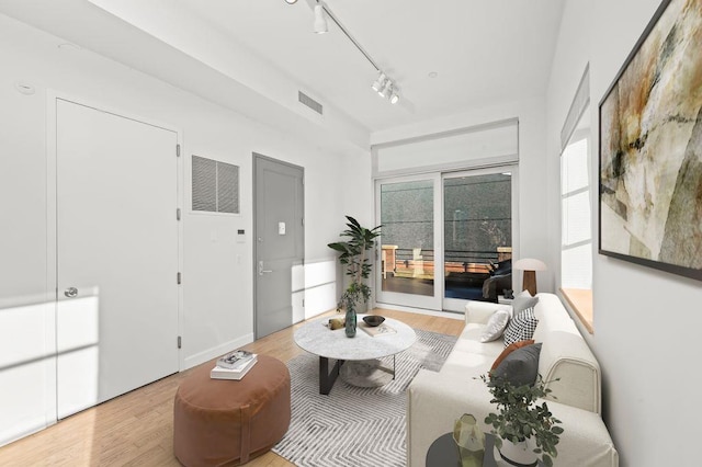 living area with wood finished floors, visible vents, and rail lighting