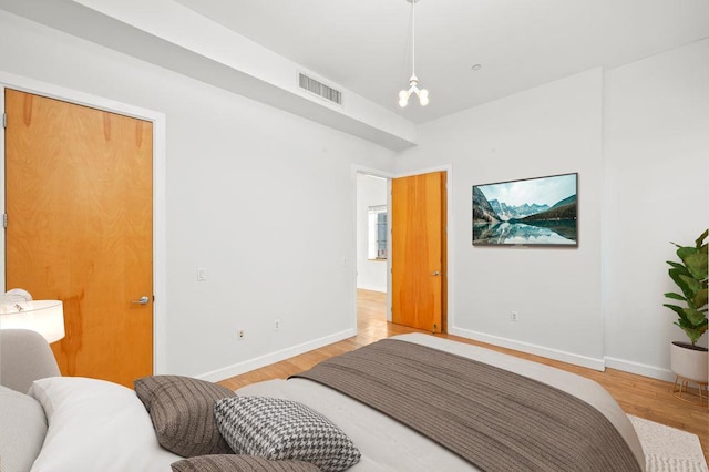 bedroom featuring light wood finished floors, visible vents, and baseboards