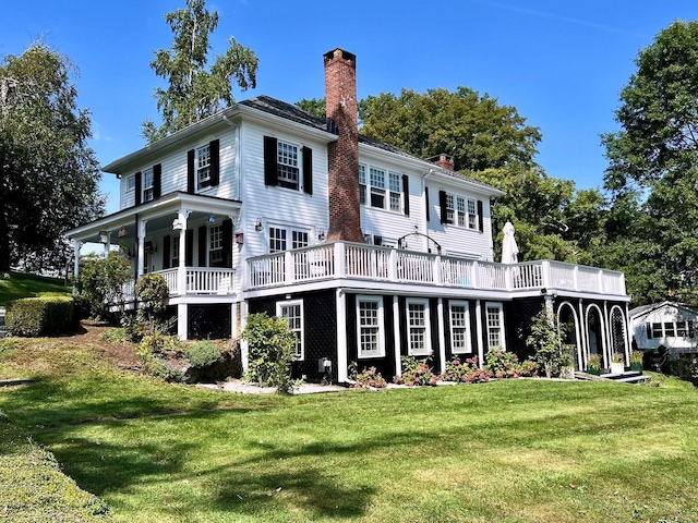 rear view of house featuring a chimney and a yard