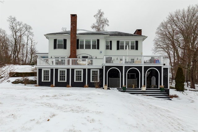 snow covered back of property featuring a chimney