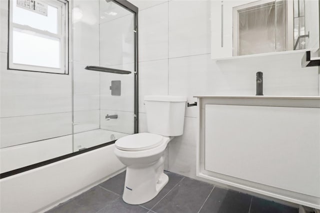 full bathroom with bath / shower combo with glass door, vanity, toilet, and tile patterned flooring