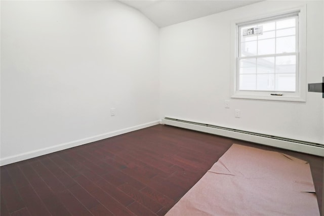 empty room featuring dark hardwood / wood-style flooring, a baseboard heating unit, and vaulted ceiling