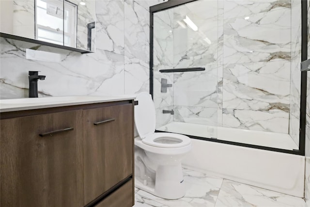 full bathroom with bath / shower combo with glass door, tile walls, vanity, and toilet