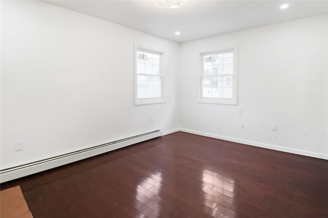 unfurnished room with dark wood-type flooring and a baseboard heating unit