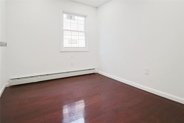 unfurnished room with a baseboard heating unit and dark hardwood / wood-style floors