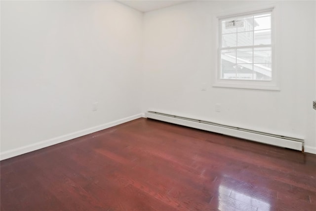 empty room featuring dark wood-type flooring and a baseboard radiator