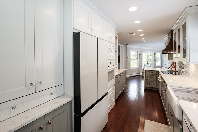 kitchen featuring white appliances, baseboard heating, white cabinetry, dark hardwood / wood-style floors, and decorative backsplash