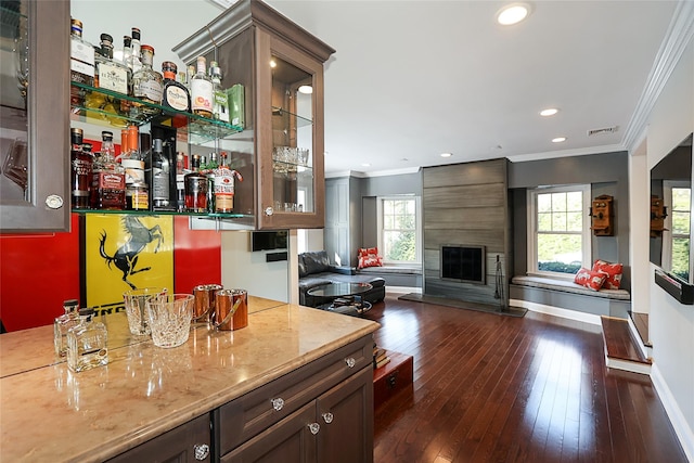 bar featuring a fireplace, ornamental molding, dark hardwood / wood-style floors, and dark brown cabinets