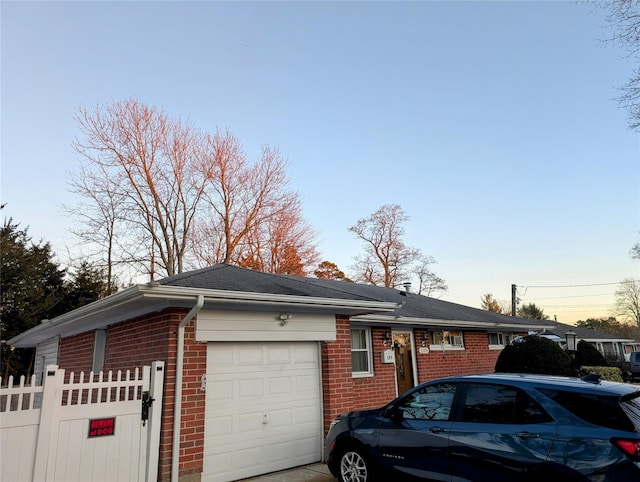 view of home's exterior featuring brick siding, a garage, and fence