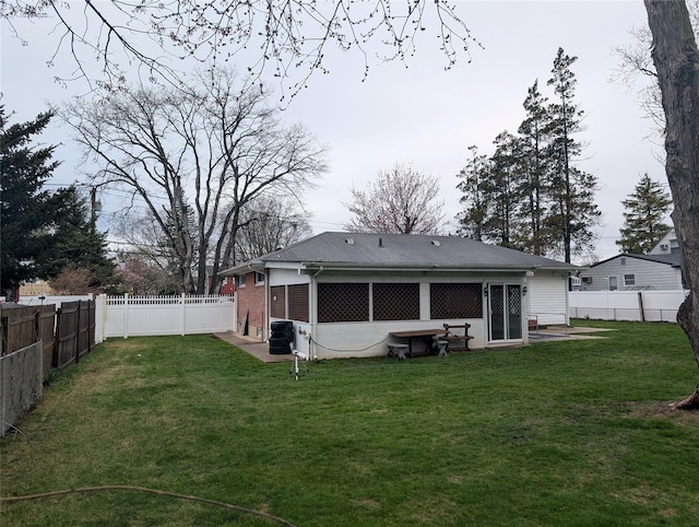 back of property featuring brick siding, a lawn, and a fenced backyard