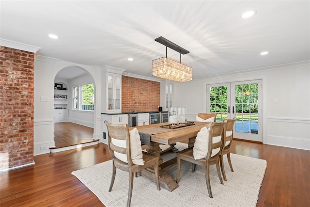 dining room with sink, beverage cooler, ornamental molding, dark wood-type flooring, and french doors