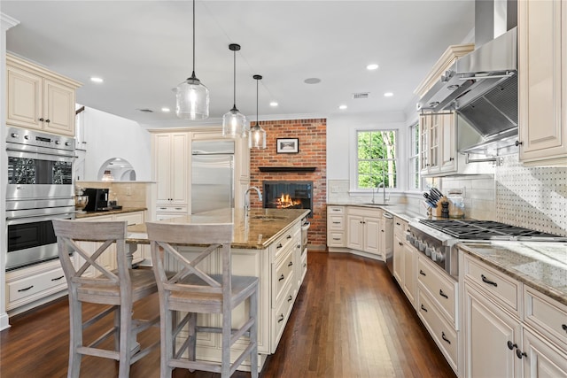 kitchen featuring appliances with stainless steel finishes, sink, a kitchen bar, hanging light fixtures, and light stone counters