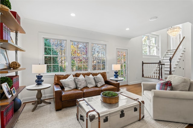 living room featuring ornamental molding, an inviting chandelier, and light wood-type flooring