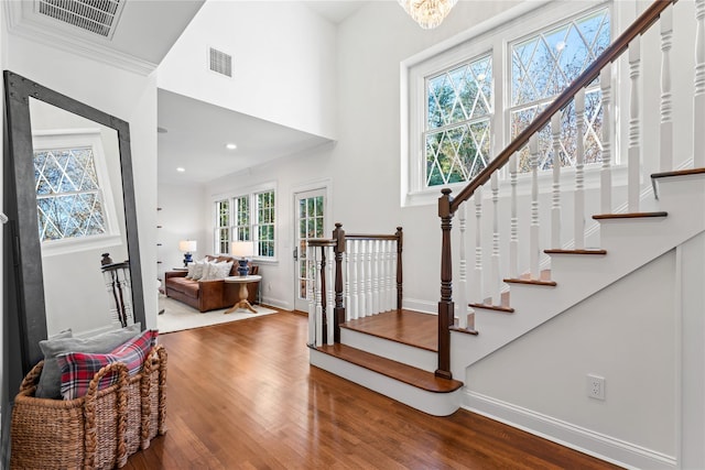 stairway featuring crown molding, a chandelier, and hardwood / wood-style floors