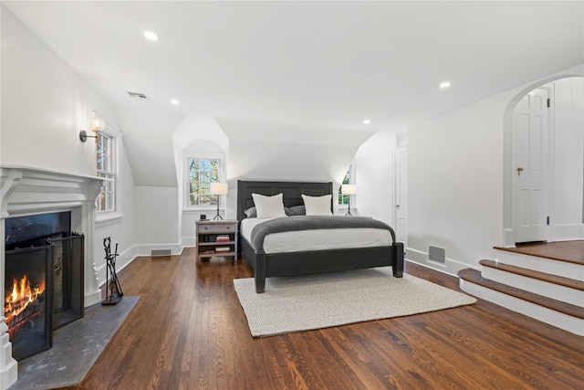 bedroom with dark hardwood / wood-style flooring, a high end fireplace, and lofted ceiling