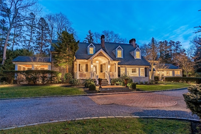 new england style home with covered porch and a front lawn