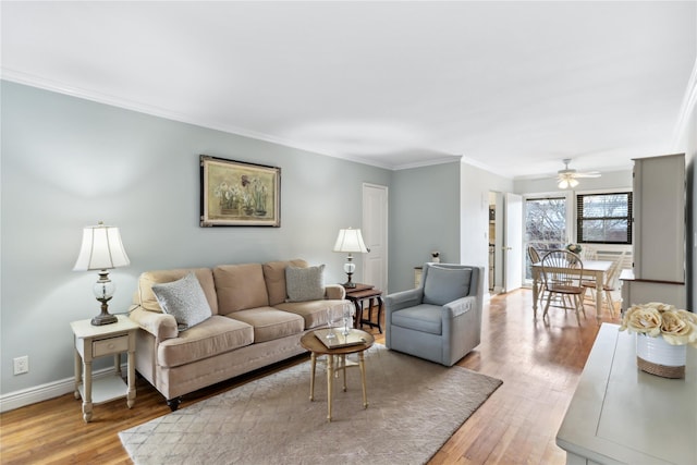 living room featuring ceiling fan, ornamental molding, and light hardwood / wood-style flooring