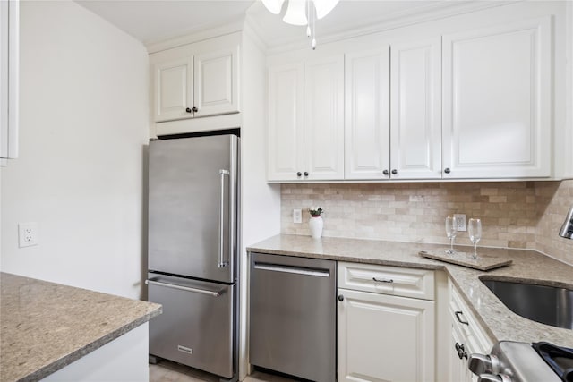 kitchen with tasteful backsplash, appliances with stainless steel finishes, sink, and white cabinets