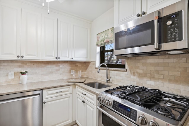 kitchen with appliances with stainless steel finishes, sink, white cabinets, and light stone counters